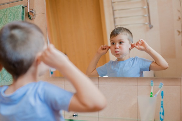 Ребенок гримасничает перед зеркалом в ванной. Premium Фотографии